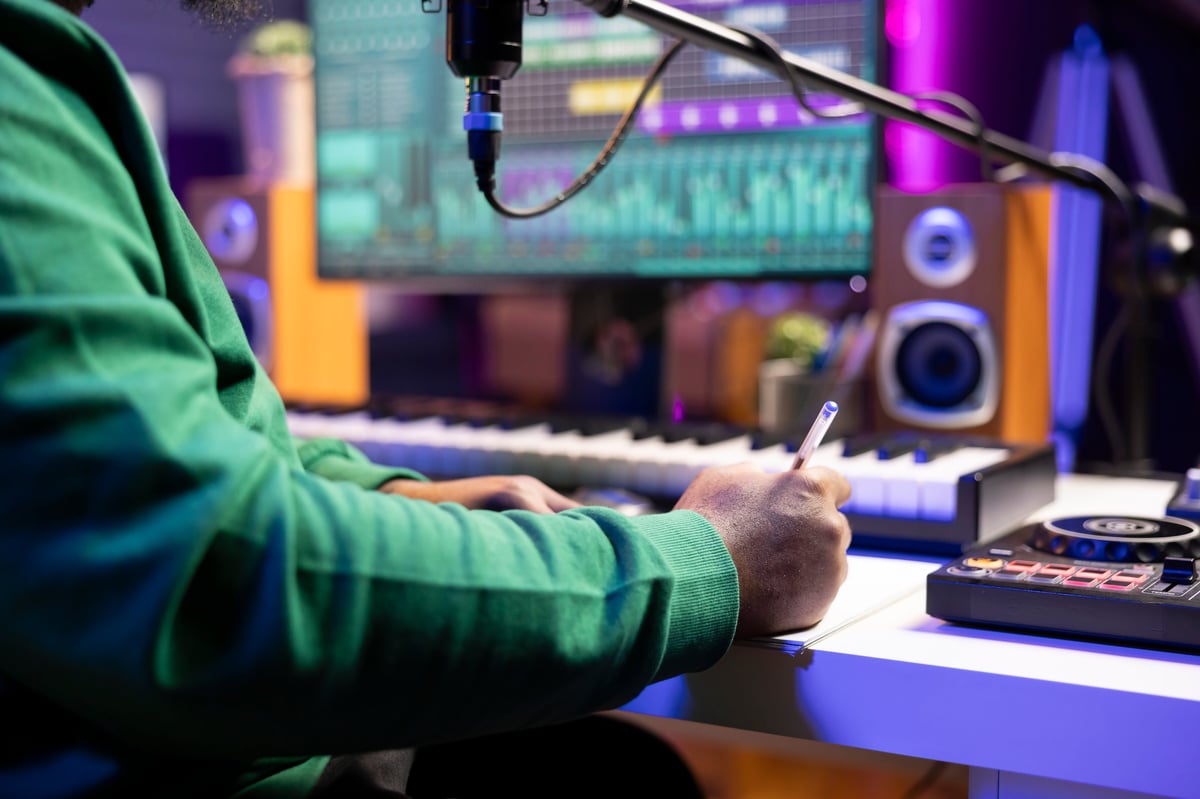 Musician taking notes on paper to produce a new track, making rhymes and blending musical elements