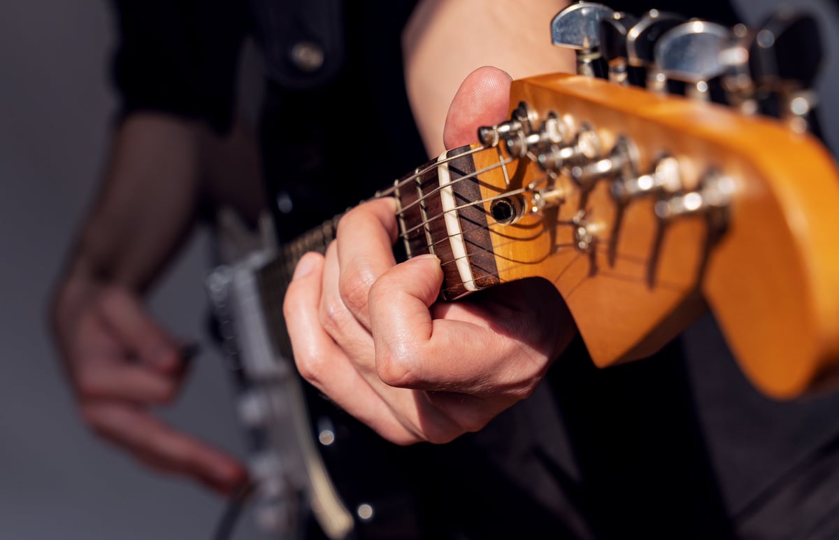 Close-up of hands playing electric guitar