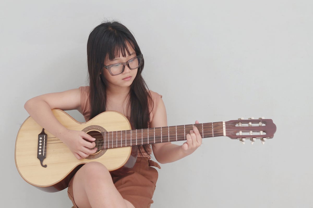 Teenage girl playing guitar with glasses