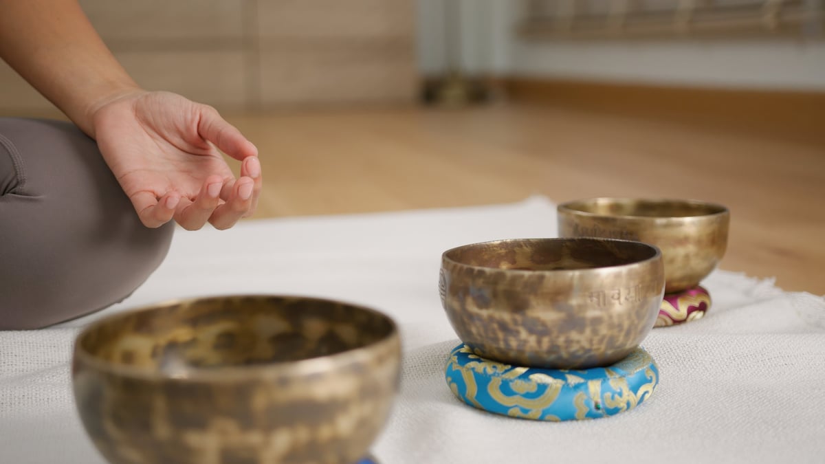 Sound healing tibetan singing bowl meditation setup with calm hand gesture and warm light