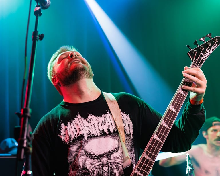 Musician performing on stage with electric guitar under blue and green stage lighting