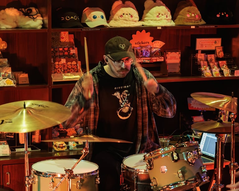 Drummer performing at drum set with cymbals in front of shelves displaying toys and collectibles